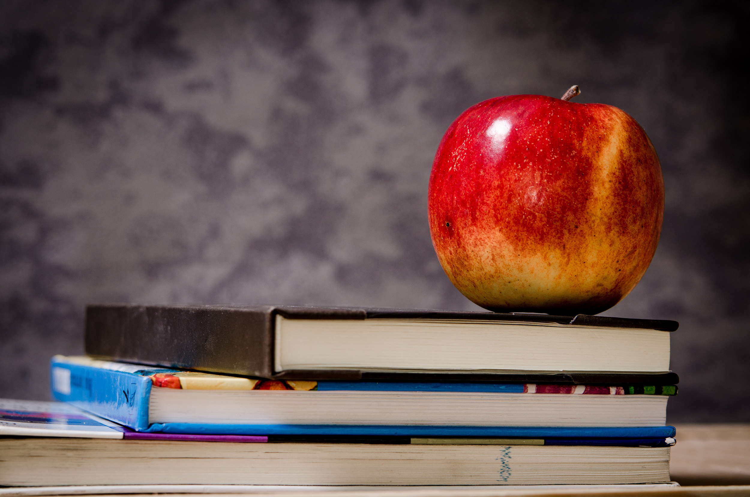 stack of books with apple on top